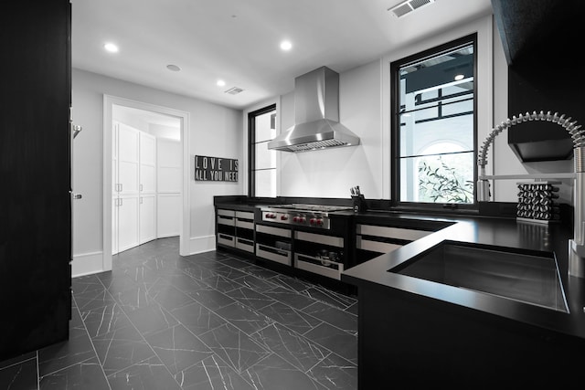 kitchen featuring stainless steel gas stovetop, sink, wall chimney exhaust hood, and dark tile floors