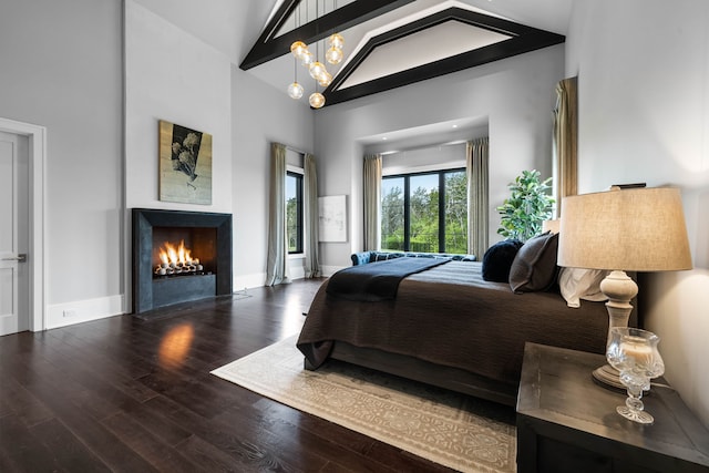 bedroom with dark wood-type flooring, high vaulted ceiling, and a notable chandelier