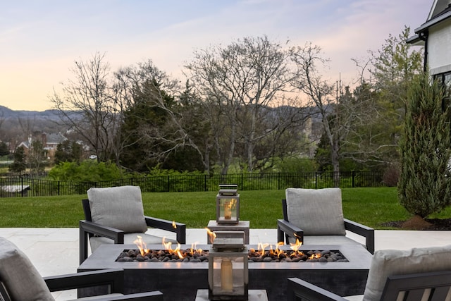 patio terrace at dusk featuring a fire pit and a lawn