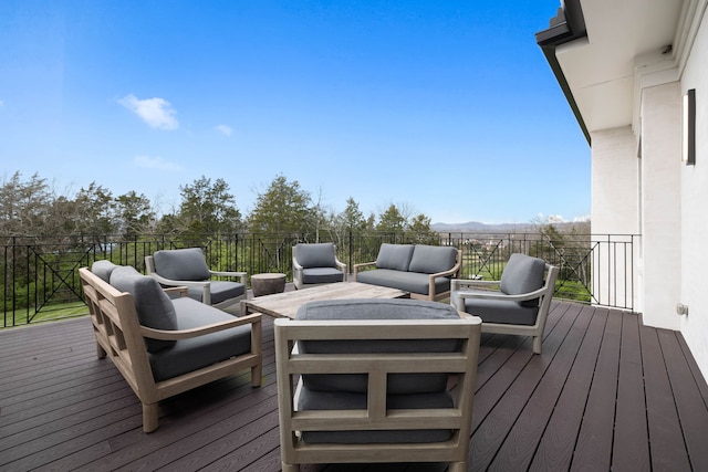 wooden deck featuring an outdoor living space with a fire pit