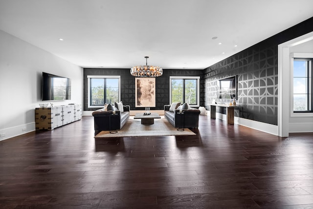 living room featuring a healthy amount of sunlight, a chandelier, and dark wood-type flooring