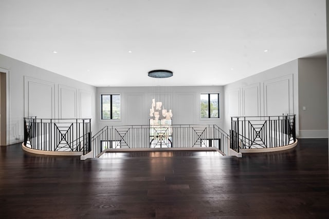 empty room featuring a healthy amount of sunlight, dark hardwood / wood-style floors, and a notable chandelier