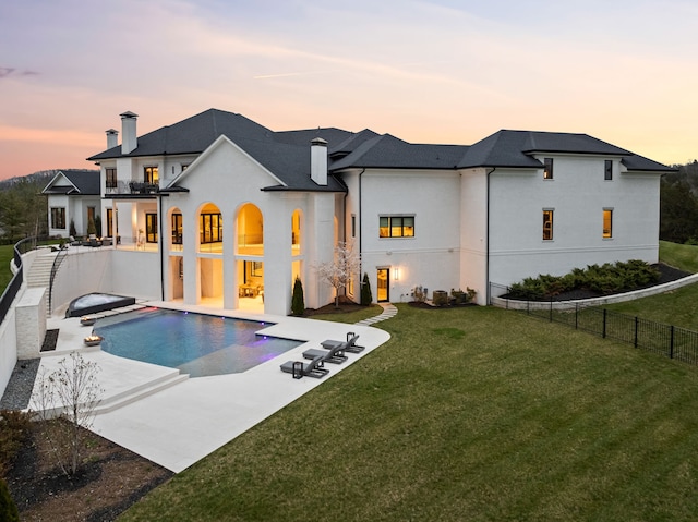 back house at dusk with a fenced in pool, a patio area, and a yard