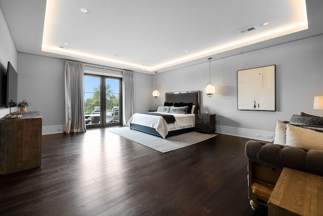 bedroom with dark hardwood / wood-style flooring, access to outside, and a raised ceiling