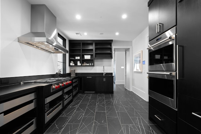 kitchen with wall chimney exhaust hood, dark tile flooring, stainless steel appliances, and sink