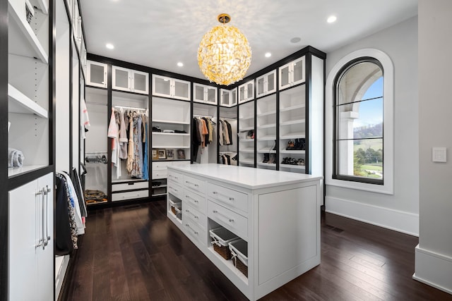 spacious closet with dark hardwood / wood-style flooring and a notable chandelier