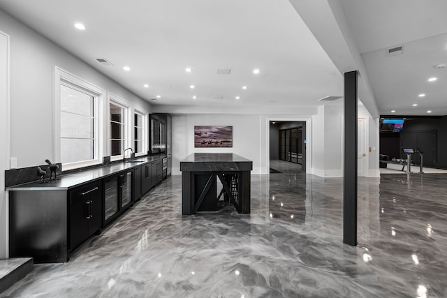 kitchen with tile flooring, wine cooler, a kitchen breakfast bar, sink, and a center island