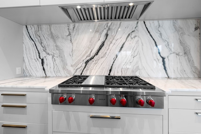 kitchen with backsplash, stainless steel gas stovetop, and white cabinets