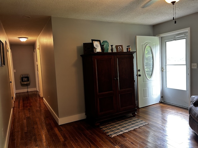 foyer entrance featuring dark wood-type flooring, baseboards, a textured ceiling, and heating unit