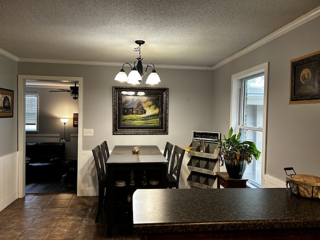 dining room with wainscoting, crown molding, and a textured ceiling