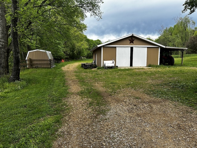 view of yard with an outdoor structure, a detached garage, and a pole building