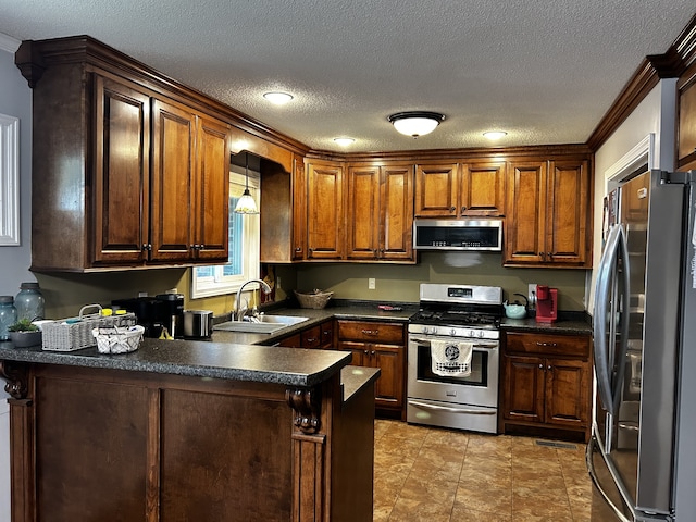 kitchen featuring dark countertops, crown molding, appliances with stainless steel finishes, a peninsula, and a sink