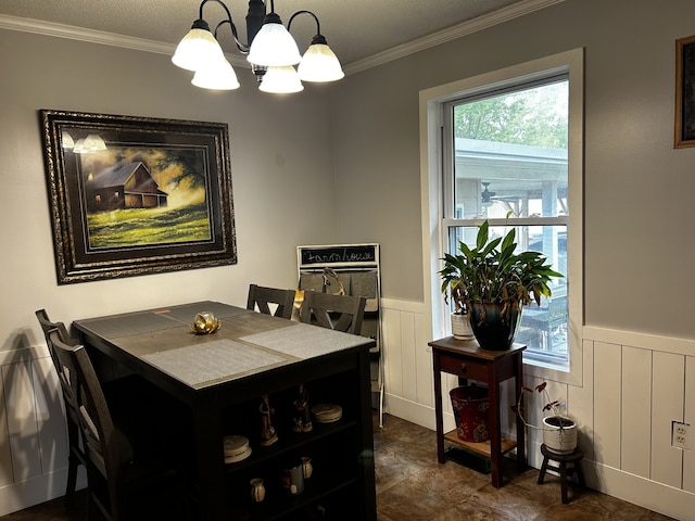 dining area with a wainscoted wall, ornamental molding, and an inviting chandelier