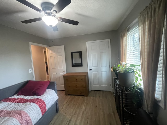 bedroom with a textured ceiling, a ceiling fan, and wood finished floors