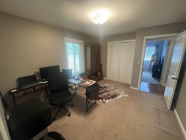 carpeted office space with baseboards and a textured ceiling