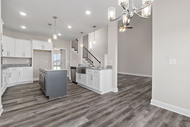 kitchen featuring hanging light fixtures, white cabinets, dark hardwood / wood-style floors, light stone counters, and a kitchen island