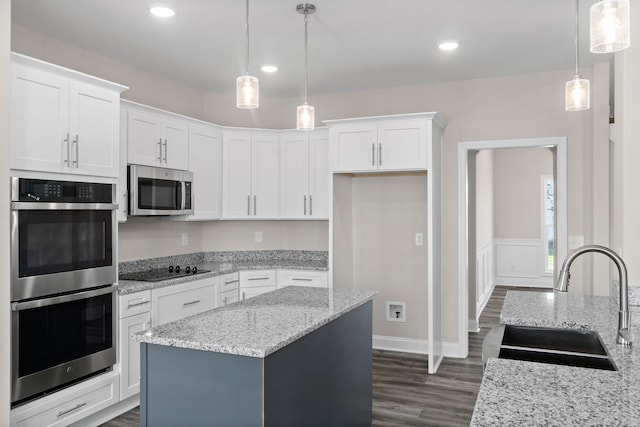 kitchen featuring dark hardwood / wood-style flooring, stainless steel appliances, sink, light stone counters, and a kitchen island