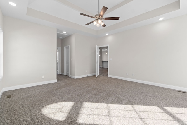 carpeted spare room with a towering ceiling, ceiling fan, and a tray ceiling