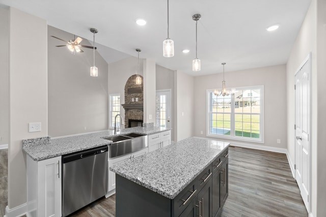 kitchen featuring sink, hardwood / wood-style flooring, a stone fireplace, and stainless steel dishwasher