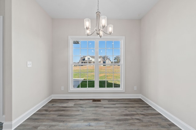 empty room with wood-type flooring and a chandelier