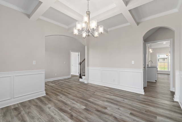 empty room with beam ceiling, dark wood-type flooring, coffered ceiling, and a notable chandelier