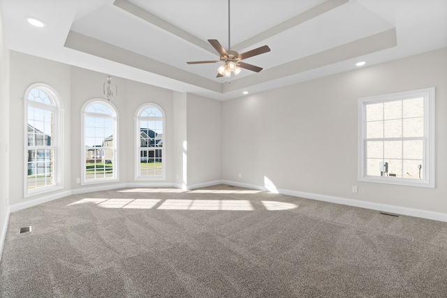 carpeted spare room featuring ceiling fan and a raised ceiling