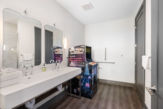 bathroom featuring hardwood / wood-style flooring, dual bowl vanity, and a shower with shower door