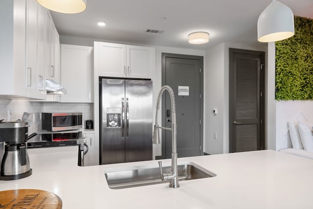 kitchen featuring decorative light fixtures, appliances with stainless steel finishes, tasteful backsplash, white cabinetry, and sink