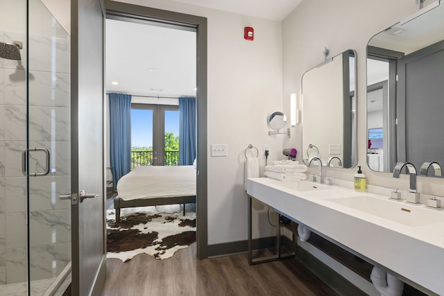 bathroom featuring wood-type flooring, an enclosed shower, dual bowl vanity, and french doors