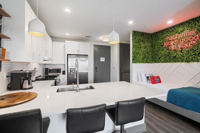 kitchen with tasteful backsplash, white cabinetry, stainless steel appliances, kitchen peninsula, and pendant lighting