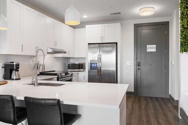 kitchen featuring a breakfast bar, white cabinetry, dark hardwood / wood-style floors, appliances with stainless steel finishes, and tasteful backsplash