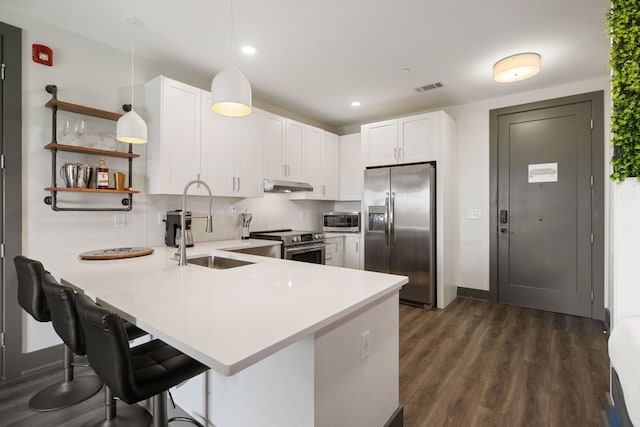 kitchen featuring decorative light fixtures, dark wood-type flooring, kitchen peninsula, stainless steel appliances, and tasteful backsplash