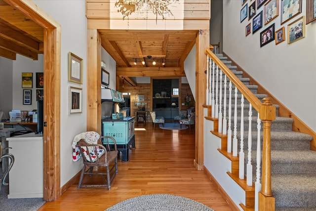 entrance foyer featuring a high ceiling, wood ceiling, a notable chandelier, hardwood / wood-style flooring, and track lighting