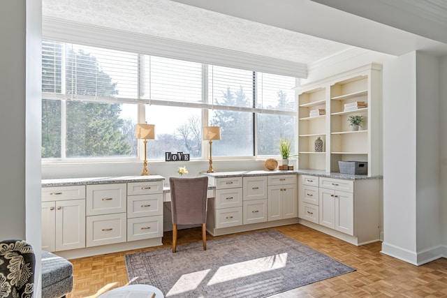 office area with light parquet floors, a wealth of natural light, and a textured ceiling