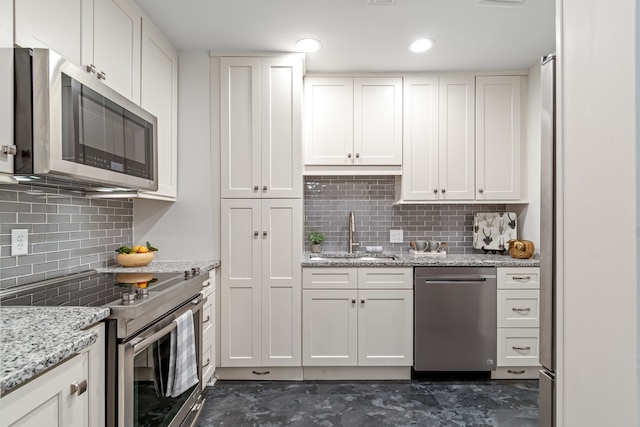 kitchen with sink, appliances with stainless steel finishes, backsplash, and white cabinetry