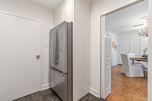 kitchen with parquet flooring, stainless steel fridge, white cabinetry, and an inviting chandelier