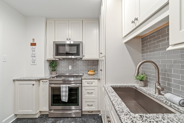 kitchen featuring backsplash, stainless steel appliances, white cabinets, sink, and dark tile floors