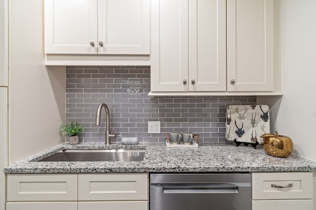 kitchen featuring tasteful backsplash, light stone countertops, sink, and stainless steel dishwasher