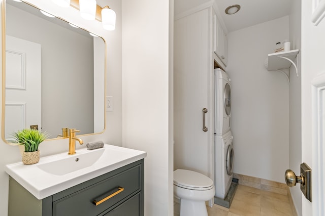 bathroom with stacked washer / dryer, vanity, tile floors, and toilet