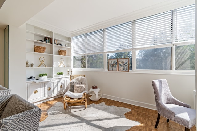 sitting room featuring a healthy amount of sunlight, built in features, parquet floors, and crown molding