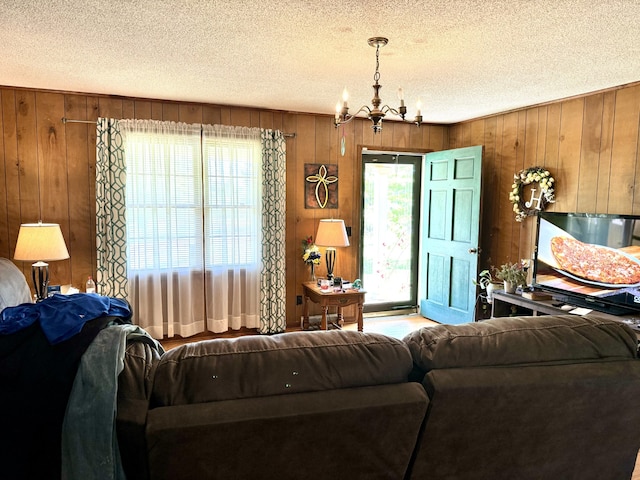 living room featuring a textured ceiling, a chandelier, and wooden walls