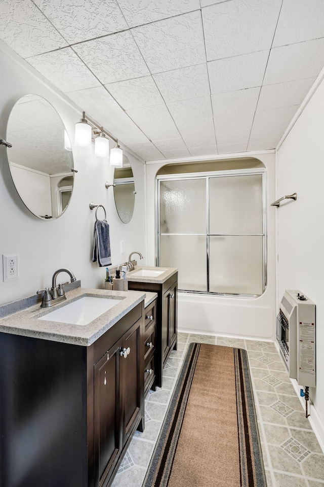 bathroom with shower / bath combination with glass door, heating unit, tile patterned flooring, and vanity