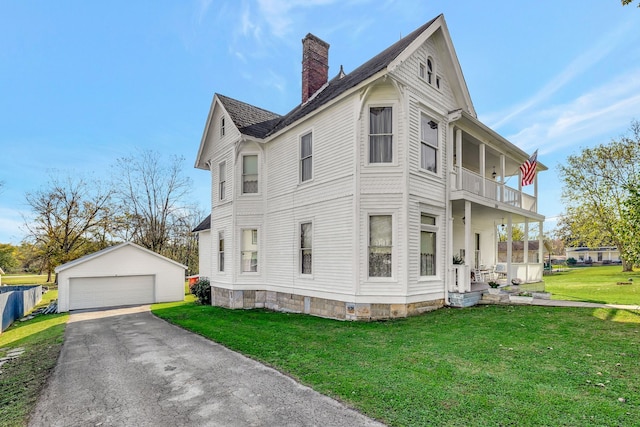 view of side of property with an outbuilding, a balcony, a garage, and a lawn