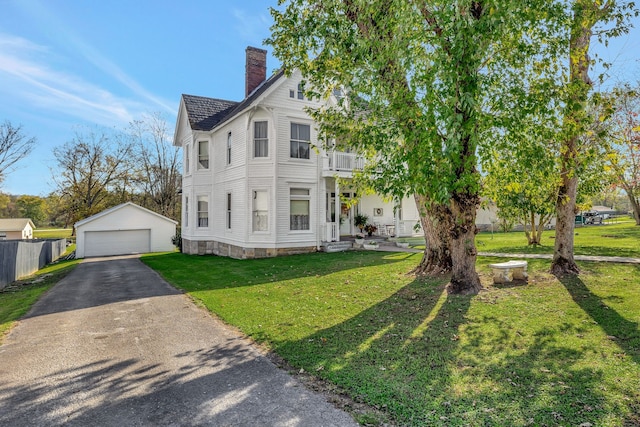 view of front of home featuring a balcony, an outbuilding, a front lawn, and a garage