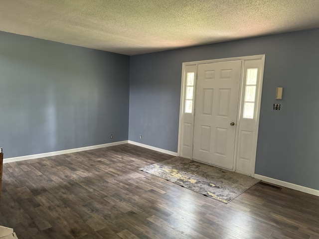 foyer entrance with dark hardwood / wood-style floors and a textured ceiling