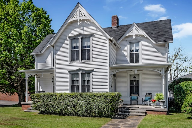 victorian house featuring a porch and a front lawn