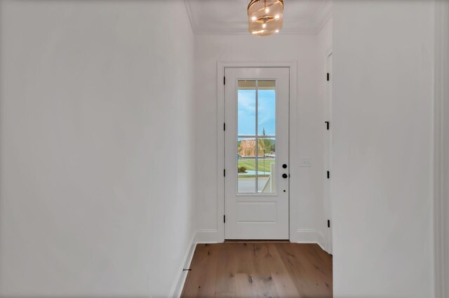 entryway with an inviting chandelier, light hardwood / wood-style floors, and ornamental molding