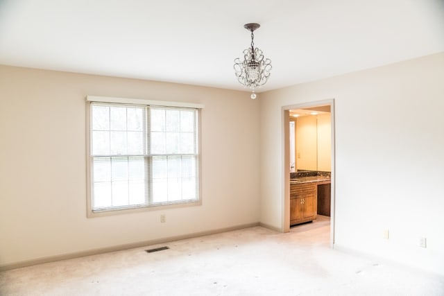 unfurnished room featuring a chandelier and light colored carpet