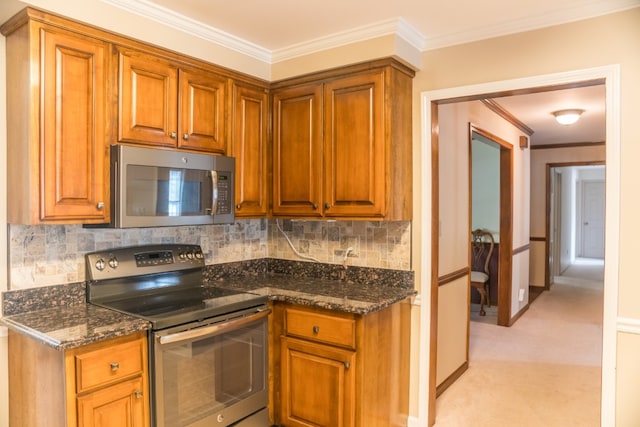 kitchen with light carpet, crown molding, dark stone countertops, appliances with stainless steel finishes, and tasteful backsplash