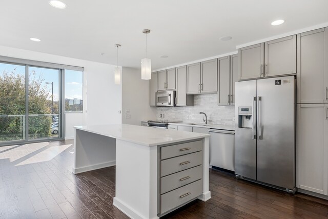 kitchen featuring a kitchen island, gray cabinetry, dark hardwood / wood-style flooring, stainless steel appliances, and pendant lighting